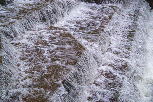 Water Cascading over Weir Steps on canal slipway showing blur blurred motion and freeze frame of water droplets for background tectures and layer effects photo
