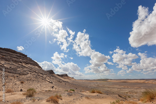 Desert landscape with mountains and sun star.