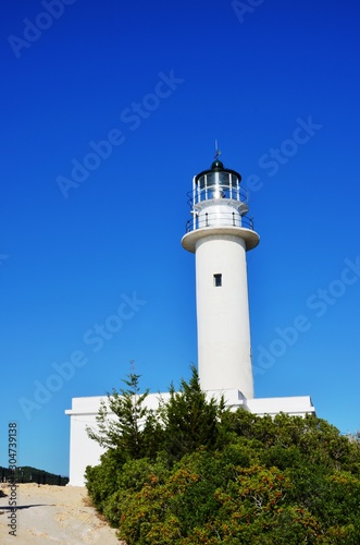 Lefkada island, Greece. 10/21/2019. white lighthouse and green trees on the edge of Lefkada island