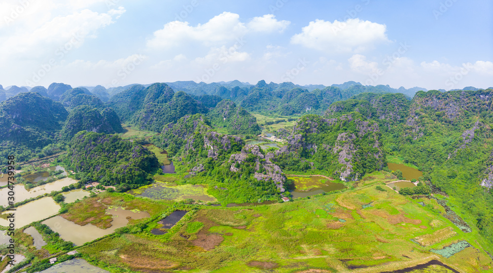 Aerial view of Ninh Binh region, Trang An tourist attraction, UNESCO World Heritage Site, Scenic river crawling through karst mountain ranges in Vietnam, travel destination.