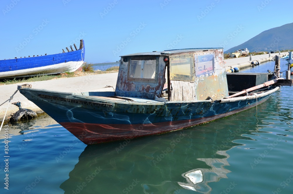 Lefkada, Lefkada Island, Greece. 10/22/2019. old, broken wooden ship blue, white and red color, fishing boat on the water in the port on the pier Lefkada, Lefkada Island, Greece. 10/22/2019. old, broken wooden ship blue, white and red color, fishing boat on the water in the port on the pier