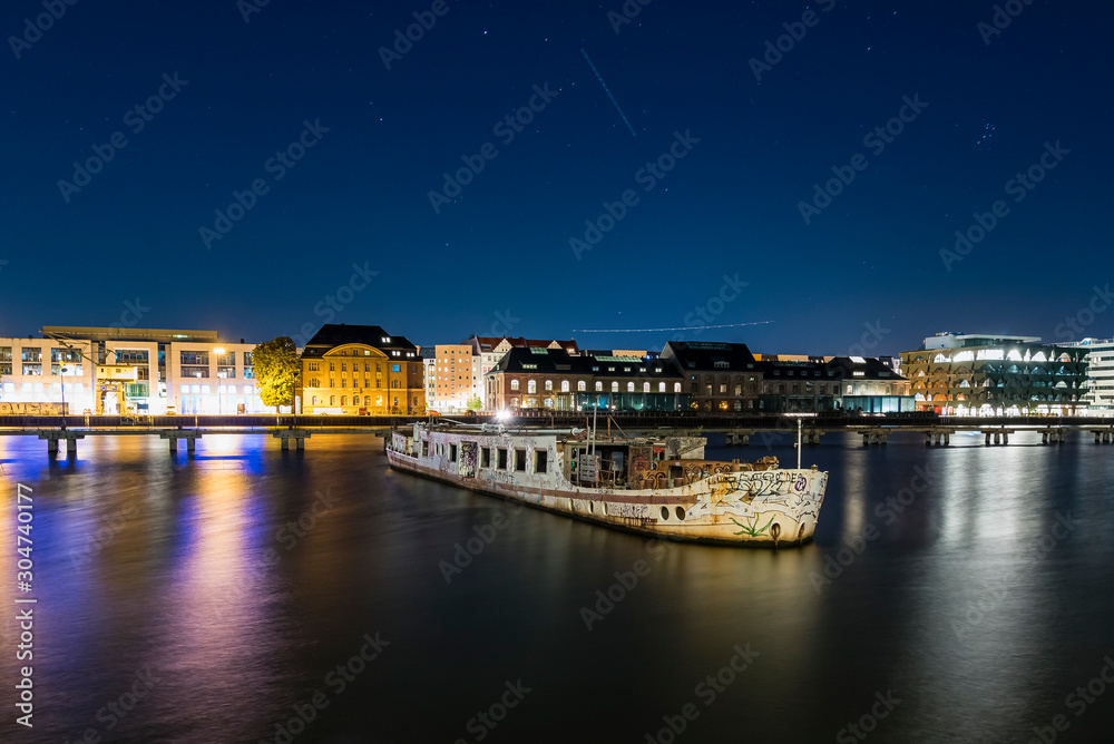 An old boat has run aground on a river, colorful night shot with a boat running aground, Berlin City, Spree,Treptower Park