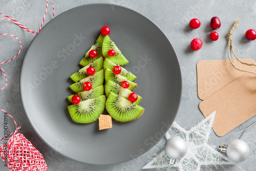 Kiwi Christmas tree with currants, funny food for kids. Christmas food background.