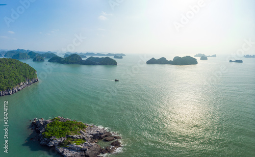 Aerial view of Ha Long Bay from Cat Ba island, famous tourism destination in Vietnam. Scenic blue sky with clouds, limestone rock peaks in the sea at the horizon.