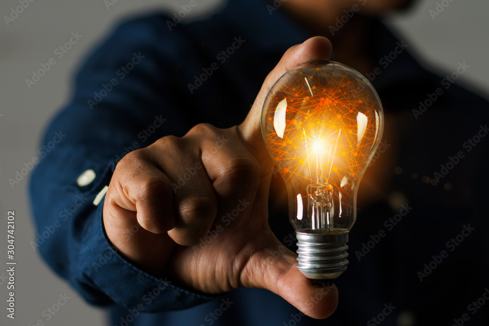 A businessman holding a light bulb in his hand demonstrates the broad vision and concept of building a business that will grow with efficiency and stability. - obrazy, fototapety, plakaty 
