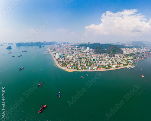 Aerial view of Ha Long Bay and Halong City skyline, unique limestone rock islands and karst formation peaks in the sea, famous tourism destination in Vietnam. Scenic blue sky and mist.