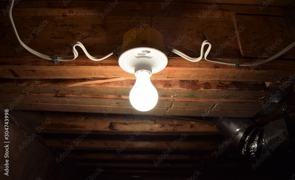 Light bulb hanging a basement ceiling Stock Photo | Adobe Stock