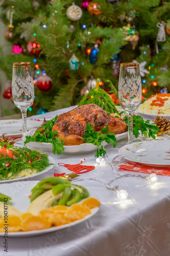 Festive Christmas served table against beautiful green pine tree decorated with many colorful new year toys. Xmas dinner, delicious food, christmas turkey. Winter holidays celebration at cozy home