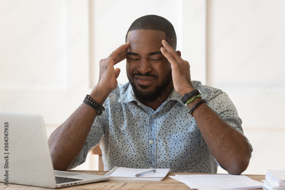 Naklejka premium Unwell african American male massage temples suffering from headache