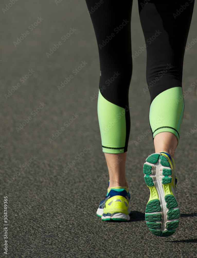 Fototapeta premium asphalt runner with black pants and green right foot in motion