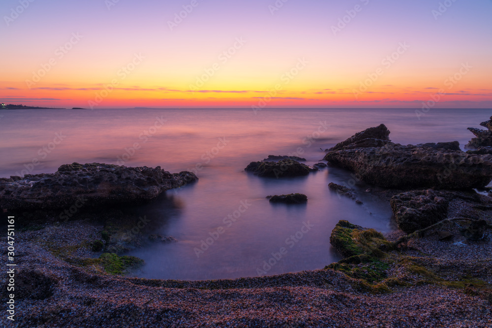 Colorful dawn on a rocky seashore, long exposure photography
