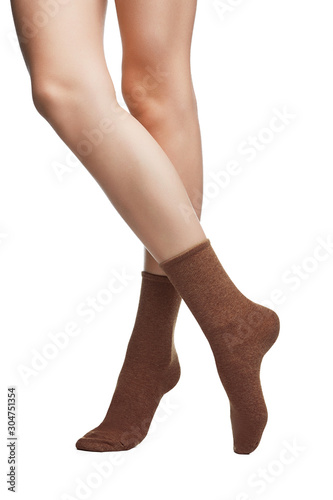 Cropped shot of a girl's cross legs, staying on a white background. It is brown socks on her foots. 