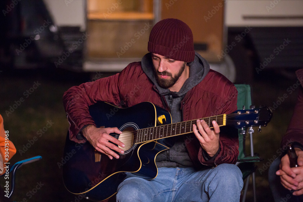 Man playing on guitar in cold night of autumn in a campsite Stock Photo