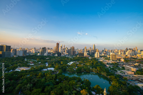Sightseeing scence of Lumpini park around modern office buildings and condominium in downtown of Bangkok city with sunset sky clouds