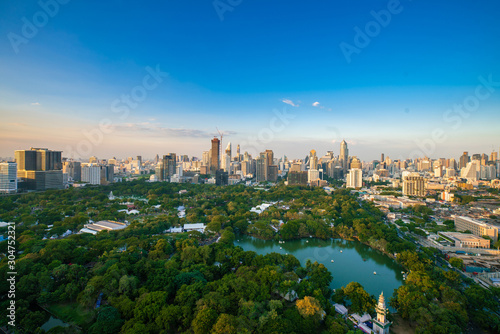 Sightseeing scence of Lumpini park around modern office buildings and condominium in downtown of Bangkok city with sunset sky clouds