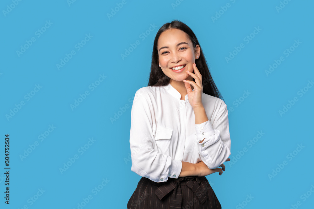 Freestyle. Young woman wearing shirt and skirt standing isolated on blue touching face posing to camera playful Freestyle. Young woman wearing shirt and skirt standing isolated on blue touching face posing to camera playful
