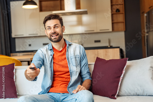 Young adult man watching tv, sitting at home © Viktoriia