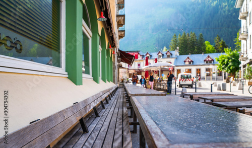 Cozy street with tables of cafe old town street in Chamonix village  France. Architecture and landmark. Cozy cityscape. Typical view of the street with tables of cafe in Chamonix.