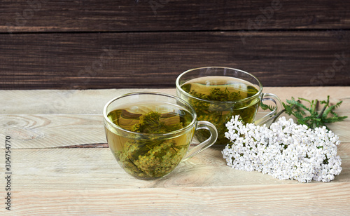 Yarrow herbal healing tea or decoction with fresh milfoil flowers nearby on rustic wooden table, closeup, copy space, alternative medicinal and naturopathy concept photo