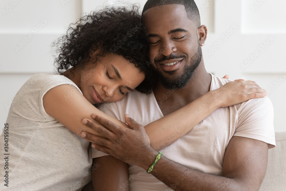 Happy African American couple cuddle hugging at home