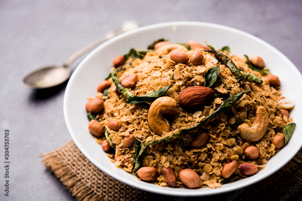 Oats Chivda / Chiwda is a healthy indian recipe with added chilli, peanuts, cashew, almond and curry leaf for flavour. Selective focus