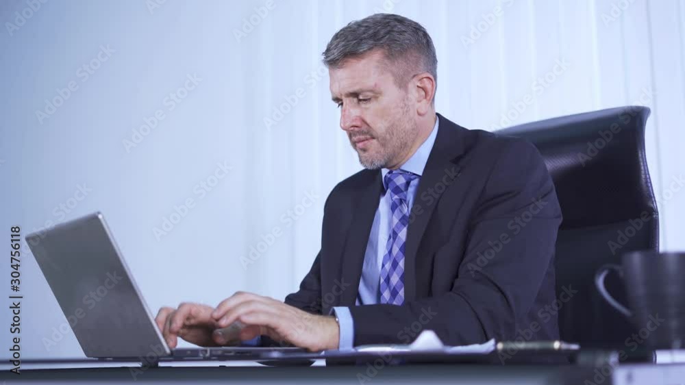 Serious Caucasian businessman typing on a laptop computer while sitting in the office. Shot in 4k resolution Serious Caucasian businessman typing on a laptop computer while sitting in the office. Shot in 4k resolution