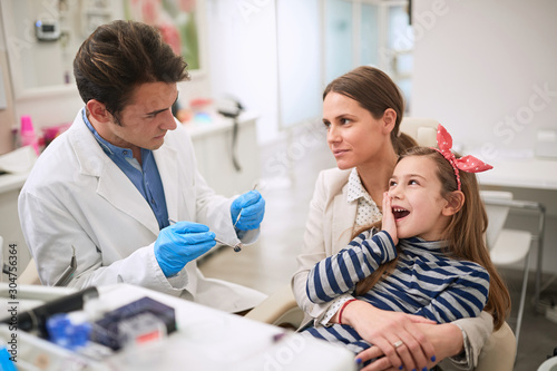 Family in dentist’s office.girl suffering from tooth pain