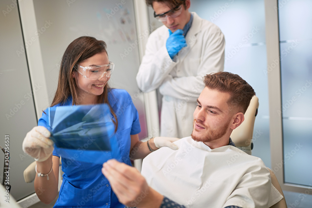 Fototapeta premium .Smiling Doctor dentist showing patient's teeth on X-ray
