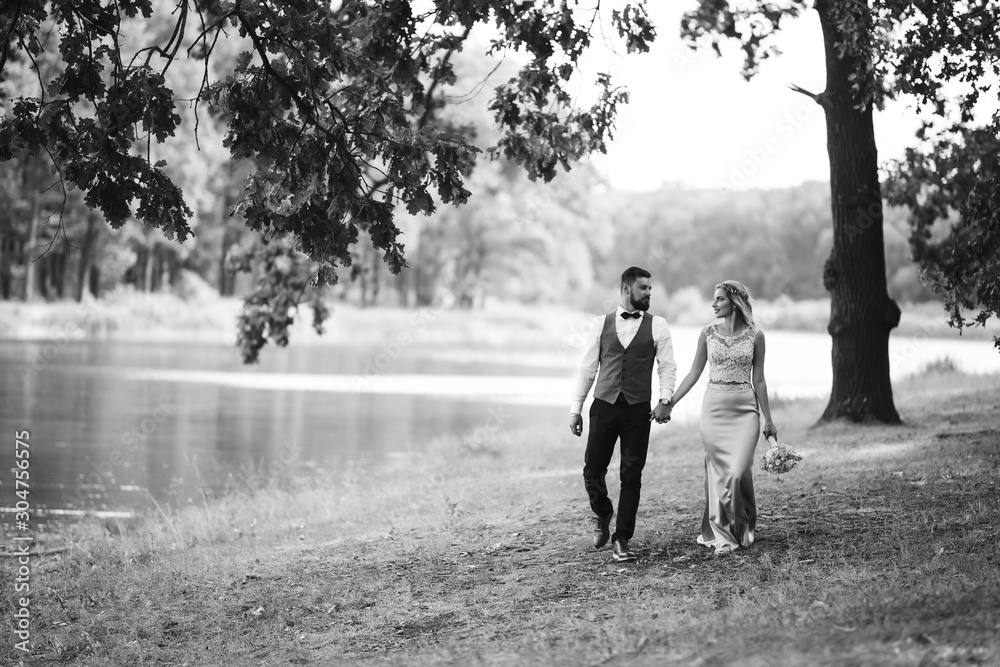 Sensual Black and white foto of bride and groom. Stylish couple of happy newlyweds posing in the park on their wedding day. Handsome bearded groom admires and kisses pretty bride. Together. Sensual Black and white foto of bride and groom. Stylish couple of happy newlyweds posing in the park on their wedding day. Handsome bearded groom admires and kisses pretty bride. Together.