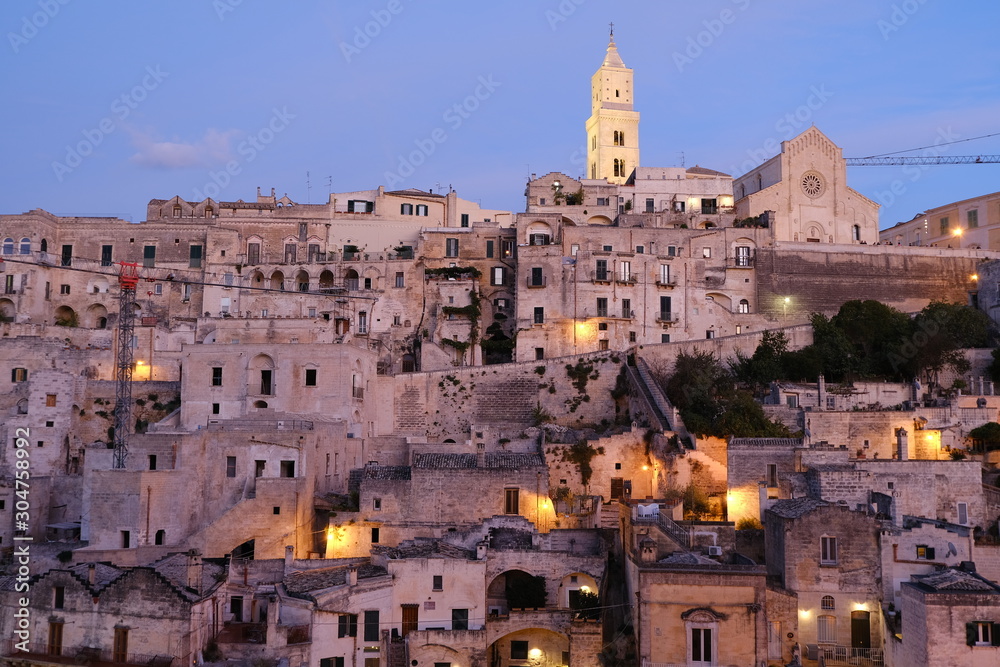 Sunset lights in the city of Matera. Bell tower, church and typical houses called Sassi.
