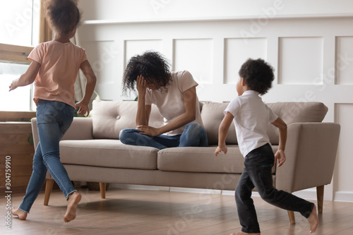 African mother sit on couch can't handle with noisy kids
