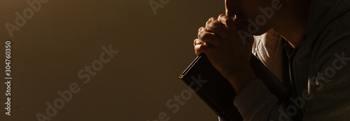 Quadro su tela Religious young man praying to God on dark background, black and white effect