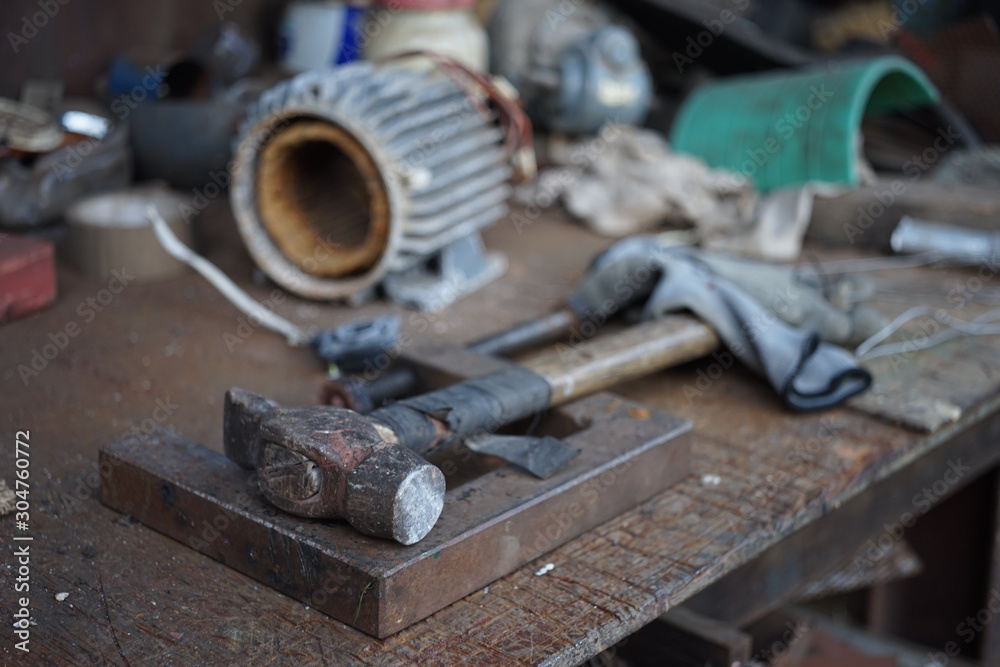 Old hammer with a wooden handle wrapped in electrical tape on a joiner's desk. Garage Tools Old hammer with a wooden handle wrapped in electrical tape on a joiner's desk. Garage Tools