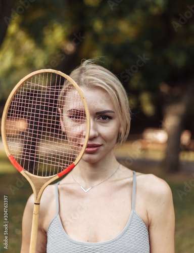 Portrait of attractive sport woman with badminton racket in the park on a bright sunny day © splitov27