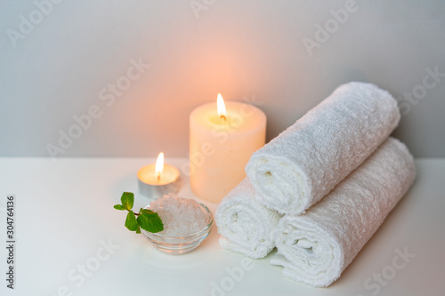 SPA and natural health concept photo. White towels, sea salt and candle lights.