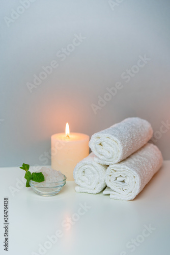 SPA procedures concept photo with candle light, sea salt and stack of towels.