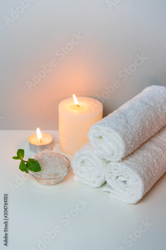 Fototapeta Naklejka Na Ścianę i Meble -  SPA treatment procedure photo with stack of towels, sea salt in a cup and candles, vertical orientation.