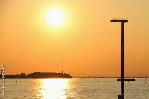 Beautiful sunset in the lagoon of, seen from the island Lido di Venezia. A street light in the foreground. Italy, Europe.
