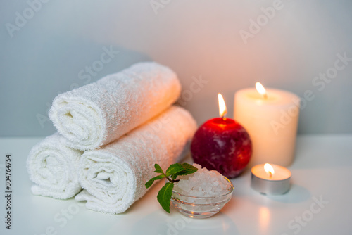 Natural health treatments of SPA. White towels, sea salt in a cup, candles.