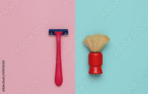 Razor, shaving brush on a pastel pink-blue background. Top view photo