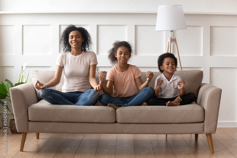 African mother with son and daughter practises yoga indoors African mother with son and daughter practises yoga indoors