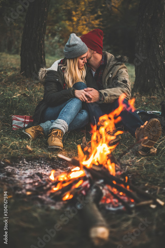Traveler couple camping in the forest and relaxing near campfire after a hard day. Concept of trekking, adventure and seasonal vacation. © zadorozhna