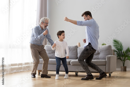 Happy grandfather, father and little son having fun, dancing together