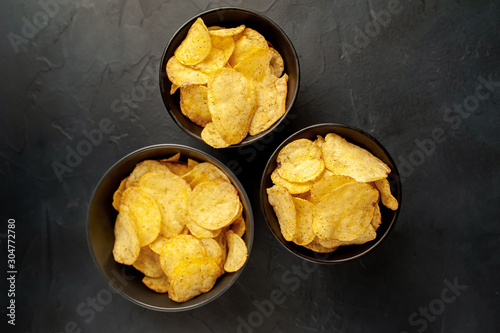 potato chips in three bowls, beer snacks on a stone background