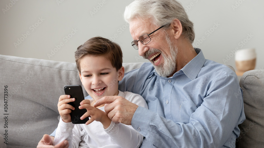 Happy grandfather and little grandson using phone, have fun together Happy grandfather and little grandson using phone, have fun together