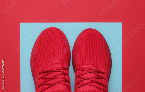 Red sports running shoes on blue-red paper background. Top view.