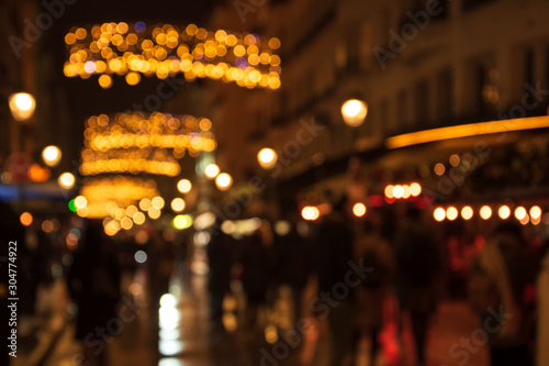 Blurry photo of Montorgueil street in Paris at night  with beautiful Christmas lights decoration and unrecognizable crowd. Winter holidays vacation and travel concept. Festive urban blurry background. photo