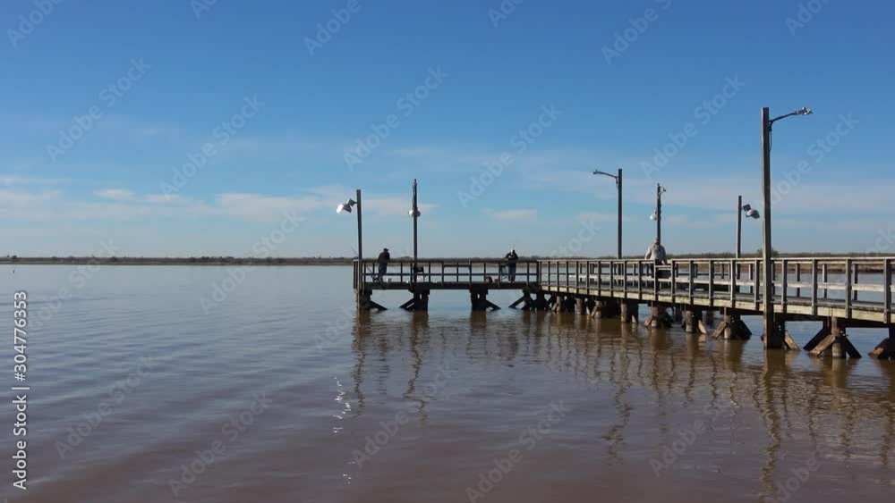 View of fishing pier and fishing people in the sunny autumn day. View of fishing pier and fishing people in the sunny autumn day.