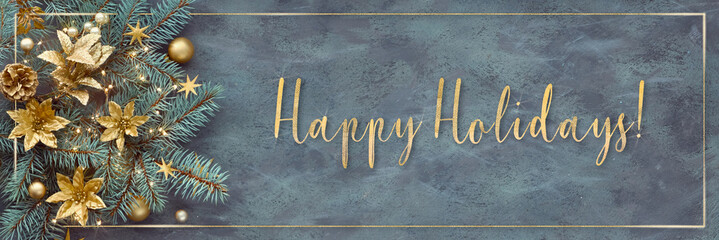 Gilded text Happy Holidays. Christmas or New Year panoramic background - fir twigs decorated with golden trinkets, flowers and Xmas lights. Top view on dark background with shiny golden frame..