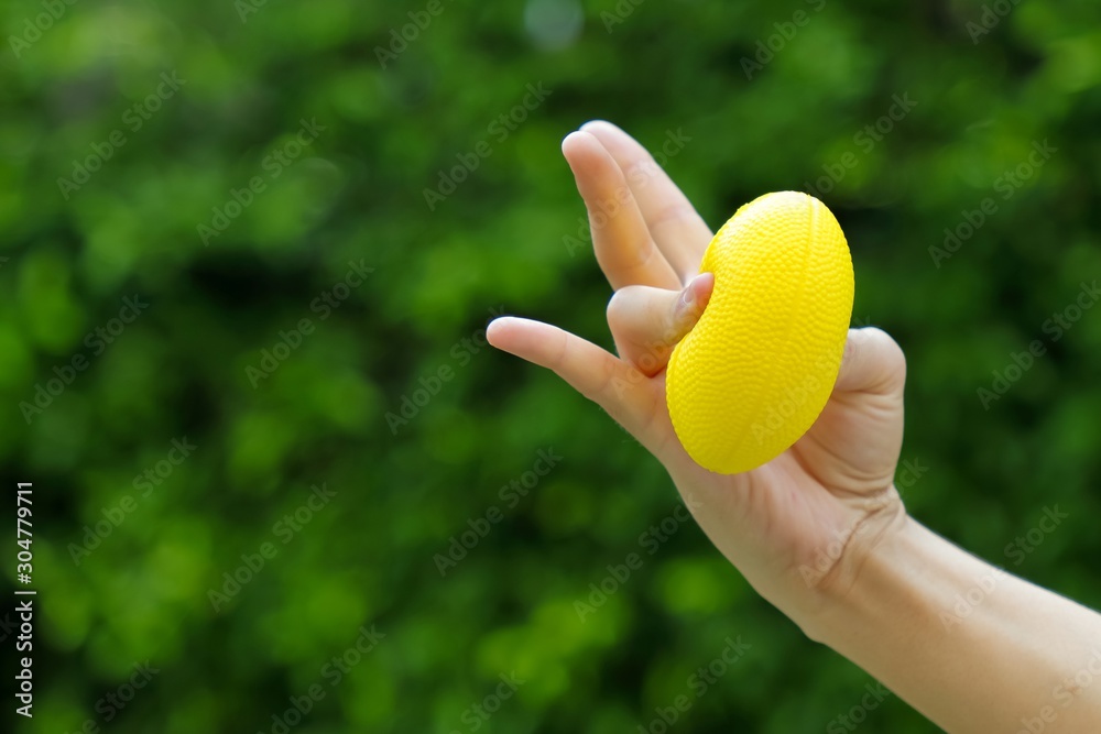 Hand holding stress ball and squeezing by thumb and ring finger for